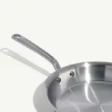A stainless steel frying pan with a long handle is set against a plain white background.