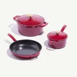 A set of three red cookware pieces, including a large pot with a lid, a small pot with a lid, and a frying pan, all featuring gold accents.