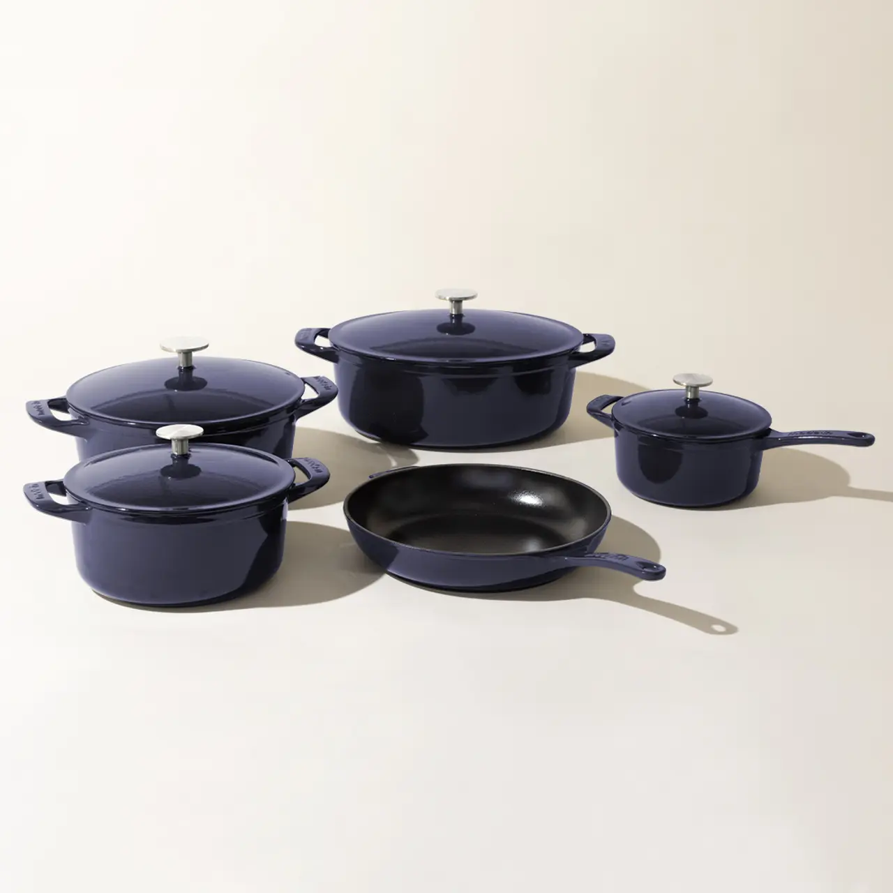 A set of matching navy blue cookware, including pots with lids and a frying pan, displayed on a neutral background.