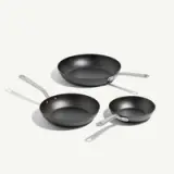 Three non-stick frying pans of varying sizes are displayed, featuring silver handles and a smooth black surface.