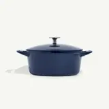 A dark blue oval Dutch oven with a lid and side handles.