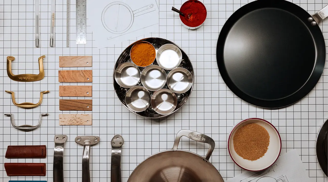 Various kitchen utensils and spices are neatly organized on a grid-lined surface.