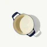 A top view shows an empty beige and blue enameled cast iron pot with two handles.