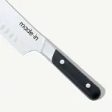 A kitchen knife with a black handle and the brand name "made.in" on the blade.