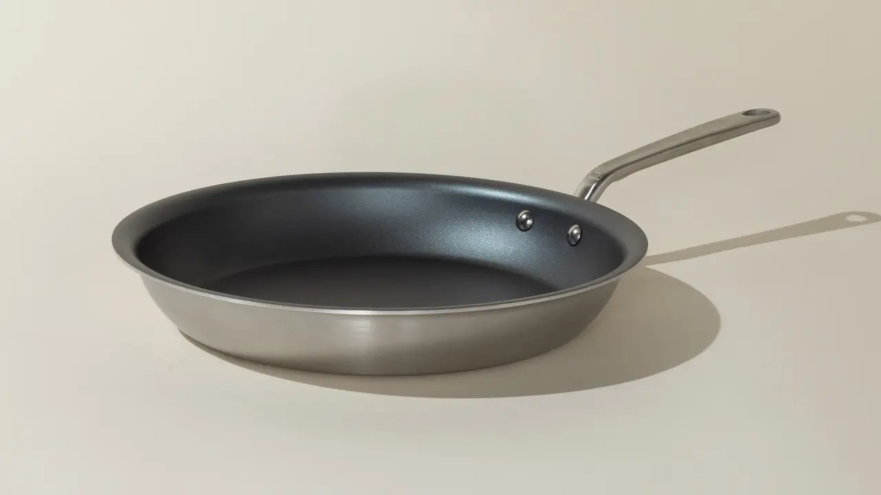 A non-stick frying pan with a metallic handle is pictured on a neutral background.
