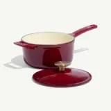 A deep red enameled pot with a cream-colored interior and a matching lid rests on a plain background.