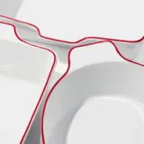 Several white ceramic dishes with red rims are shown close-up, stacked together.