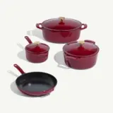 Four pieces of red cookware, including a large pot, a medium pot with a lid, a small pot, and a frying pan, are displayed together.