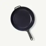 A dark-colored cast iron skillet with a smooth interior and a short handle.