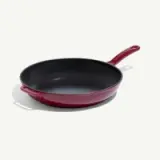 A red cast iron skillet with a black interior and a handle.