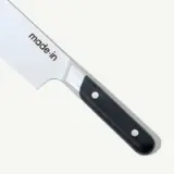 A chef's knife with a black handle and the brand name "made-in" on the blade.