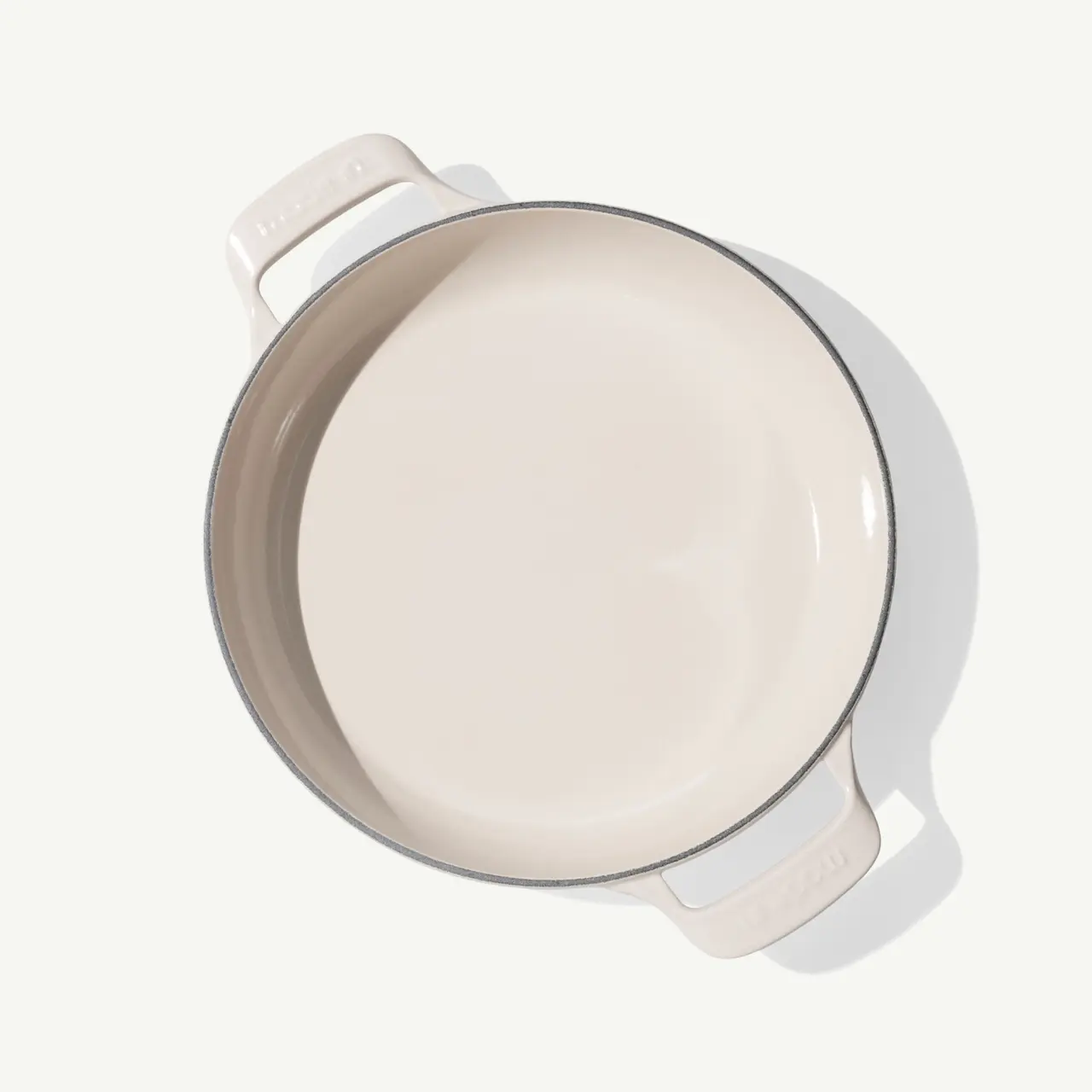 A round, beige cooking pot with two handles, featuring a smooth, glossy interior.