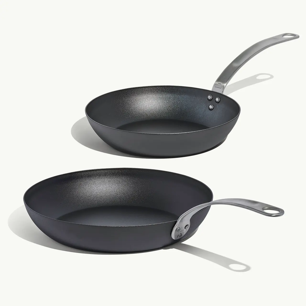 Two non-stick frying pans with sleek black surfaces and stainless steel handles, positioned one on top of the other.