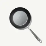 A sleek, non-stick frying pan with a silver interior and a stainless steel handle is positioned against a light background.