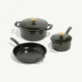 A set of three cooking pots and pans in dark green with gold accents, including a large covered pot, a smaller covered pot, and a frying pan.