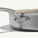 A close-up view of a stainless steel frying pan with a sleek handle and a "made-in" logo on the side.