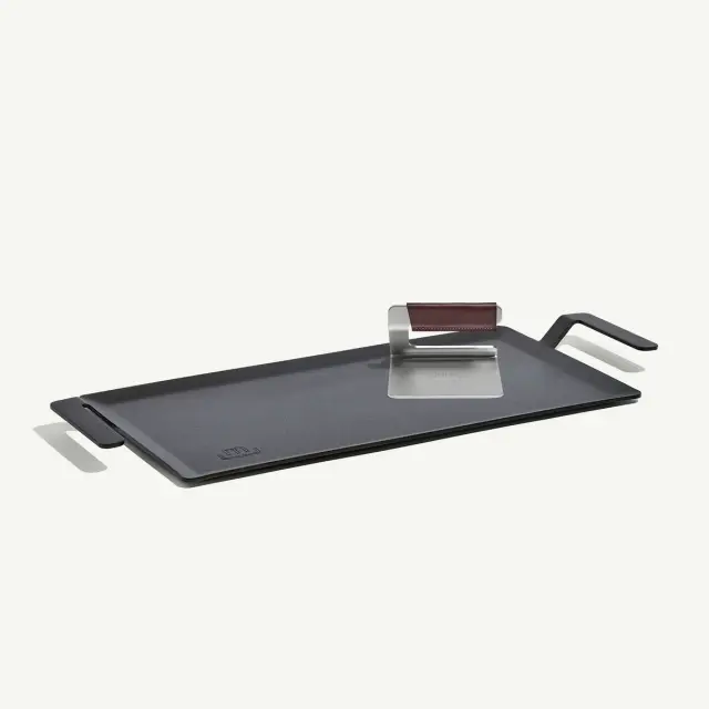 A rectangular griddle pan with handles and a metal grill press is shown against a white background.