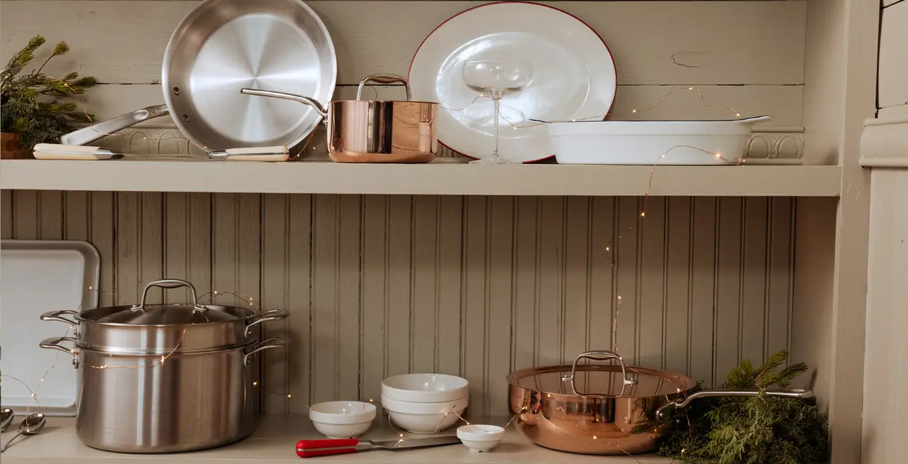 A variety of pots, pans, and dishes neatly arranged on a kitchen shelf, creating a homey and organized look.