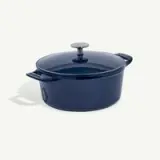 A blue, round, enameled cast iron Dutch oven with a lid and handles on both sides.