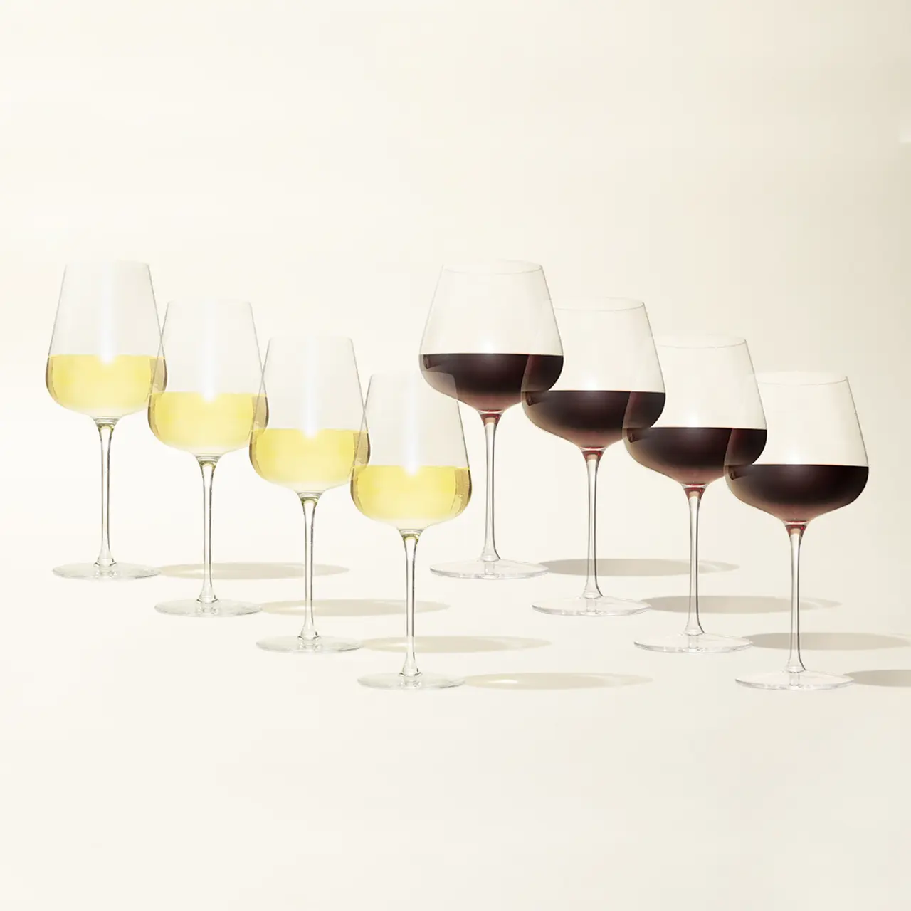 Seven wine glasses in a row, with the first three containing white wine and the last four containing red wine, on a light background.