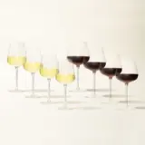 Seven wine glasses in a row, with the first three containing white wine and the last four containing red wine, on a light background.
