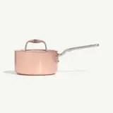 A copper saucepan with a long handle and lid is displayed against a plain background.
