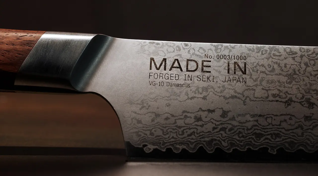 A close-up view of a Japanese chef's knife with "MADE IN SEKI, JAPAN" text and a decorative pattern etched on the blade.