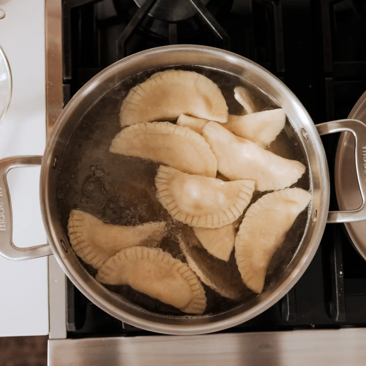 A pot of boiling dumplings cooks on a stovetop.