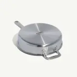 A stainless steel pan with two handles and a logo stamped on the bottom lies on a white background.