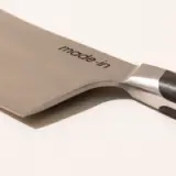 A close-up of a knife blade with the inscription "made.in" visible on its side.