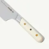 A close-up of a knife with a light-colored handle and "made•in" engraved on the blade.