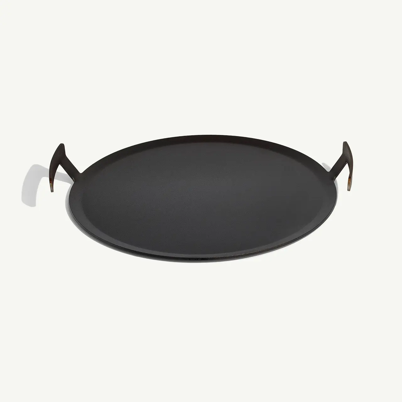 A black round paella pan with two handles attached to opposite sides.