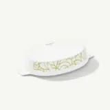 A white oval ceramic baking dish with green decorative patterns on the sides.