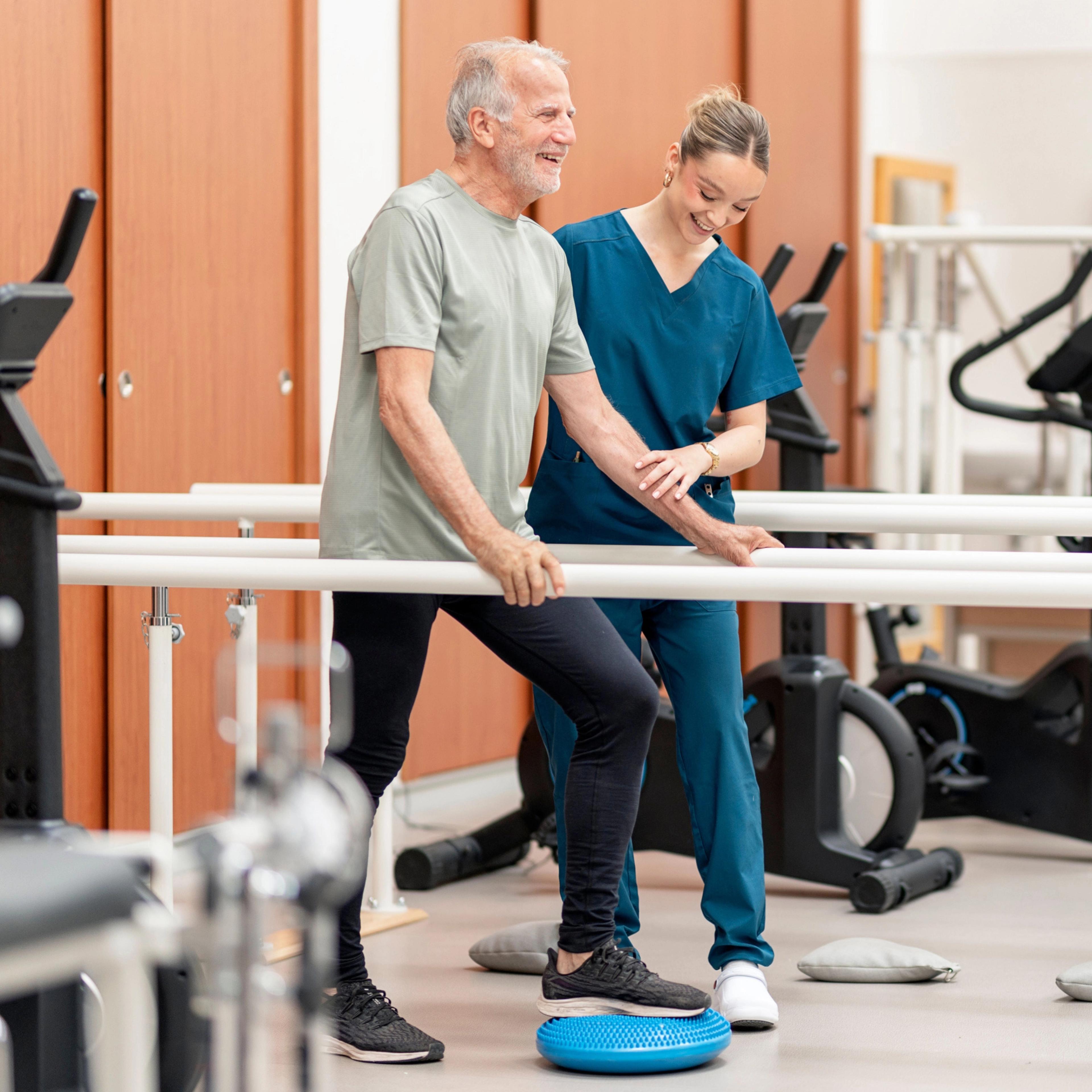 A HealthPro Heritage physical therapist helps a patient using a rolling walker in a bright clinic