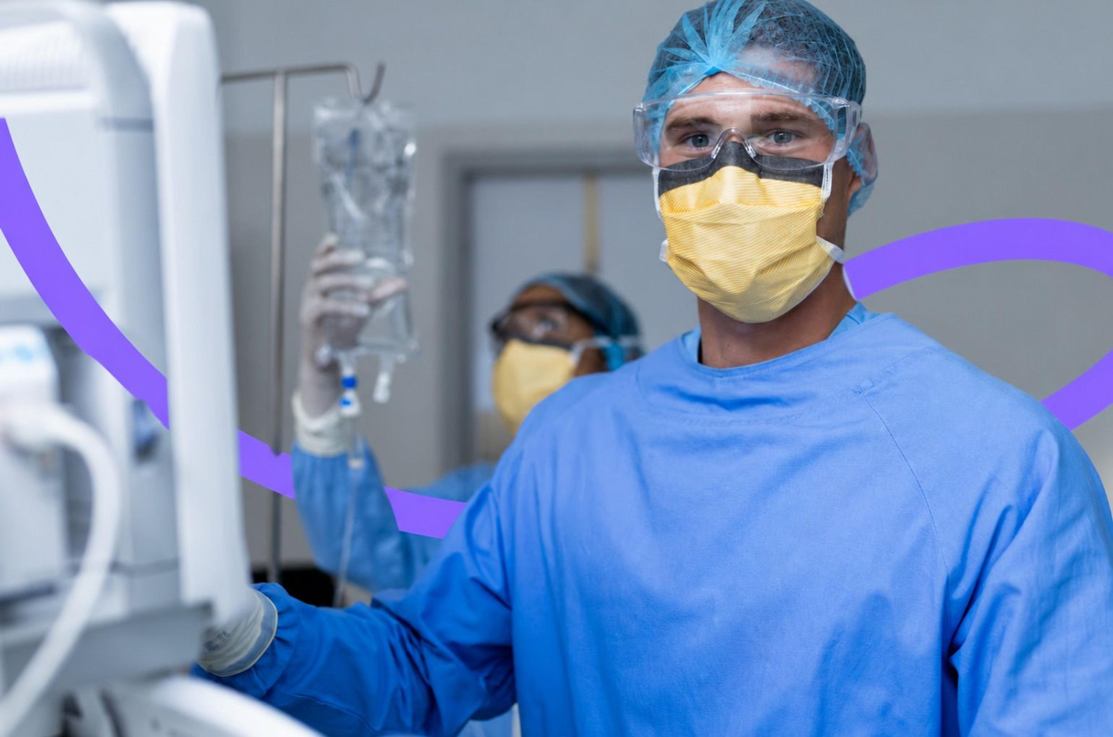 A nurse anesthetist in a surgical gown and mask adjusting an IV line in an operating room
