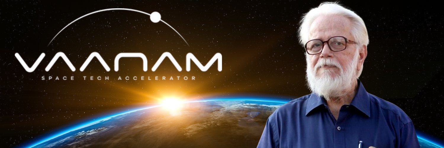 A banner image for Vaanam, a space tech accelerator, featuring its logo prominently displayed against a backdrop of space and a sunrise over Earth. On the right side of the image is a portrait of Nambi Narayanan, former ISRO scientist, who is mentoring the accelerator. The logo includes a stylized arc representing a satellite orbit, with the text "Vaanam Space Tech Accelerator" beneath it. The overall design emphasizes the space theme and the involvement of a prominent figure in India's space research.