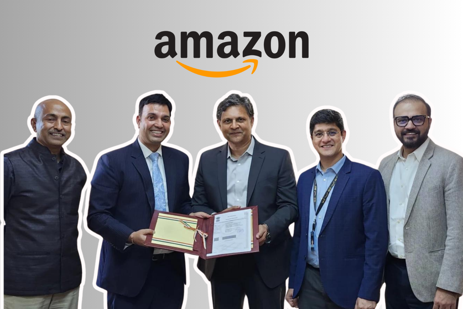 The image shows five men standing in a row, all dressed in formal business attire. The central two figures are holding a certificate or award folder, while smiling toward the camera. Above them is the Amazon logo, indicating an official or celebratory moment related to Amazon. The background is light grey, and the figures are outlined with a subtle white border, giving them a standout appearance.