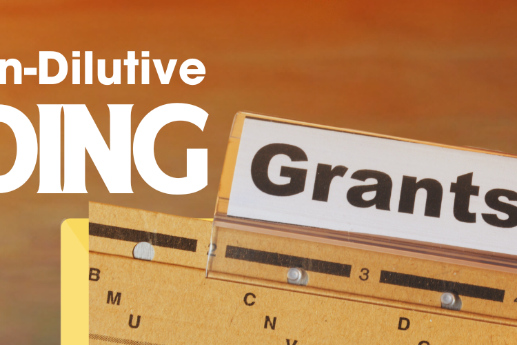 A banner titled "Finding Non-Dilutive Funding" featuring a close-up image of a hand pulling out a card labeled "Grants" from an organized file system. The background is warm and gradient, with the text "Finding Non-Dilutive Funding" prominently displayed in bold, white, and black letters on the left side.