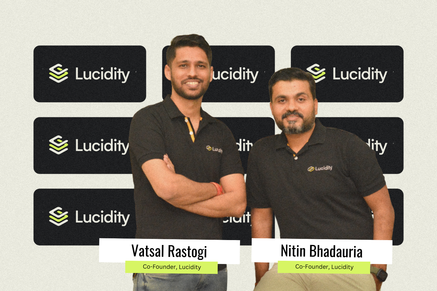 A photograph of two co-founders of Lucidity, Vatsal Rastogi and Nitin Bhadauria, standing side by side and smiling at the camera. They are wearing black polo shirts with the Lucidity logo. The background features multiple "Lucidity" logos on black rectangular panels. Name tags are placed on each individual, with Vatsal Rastogi and Nitin Bhadauria both labeled as Co-Founders of Lucidity.