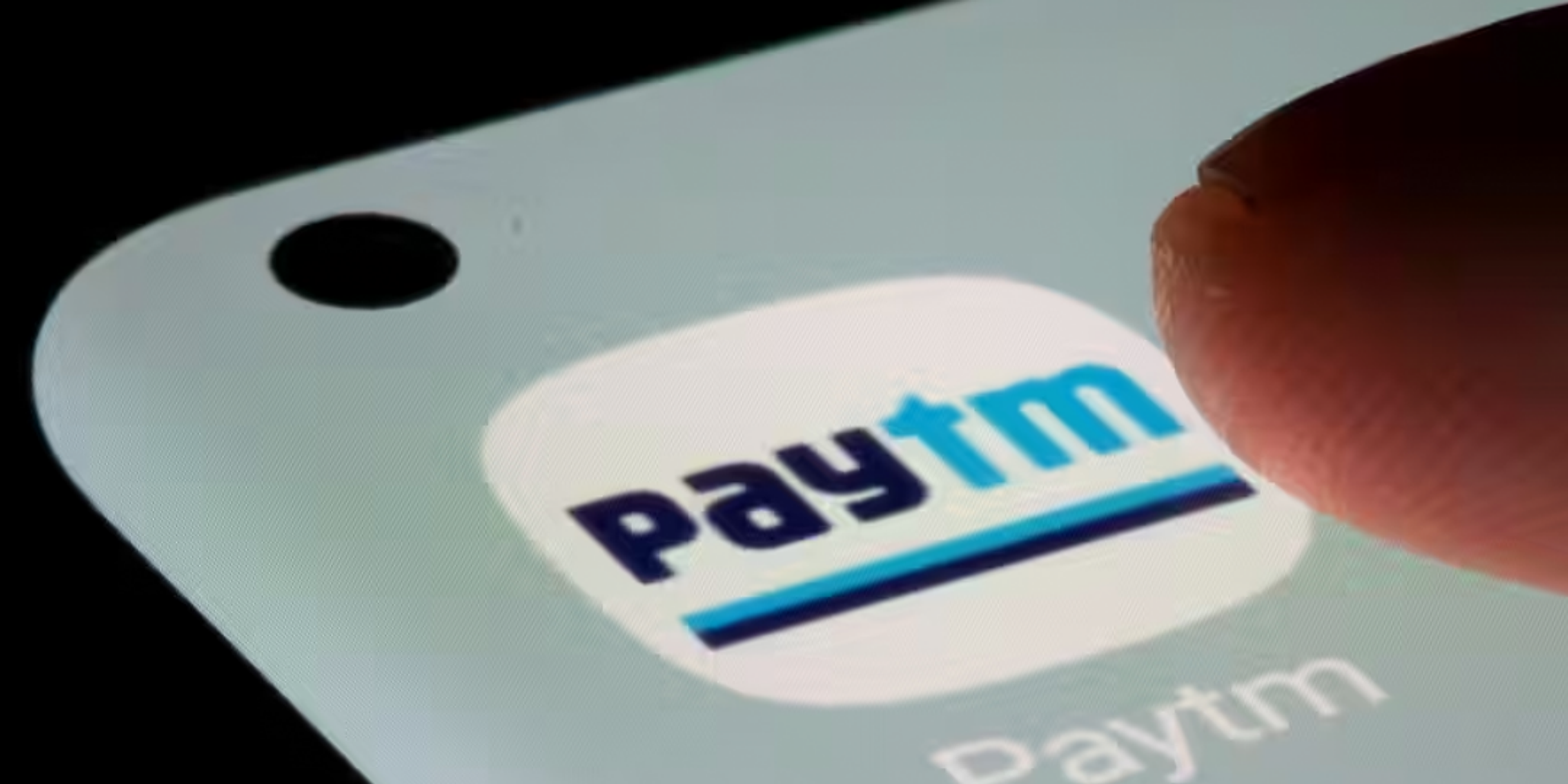 Image of a person clicking on Paytm icon on a phone, Text on top describing the fall of Paytm stock price below 400 rupees.