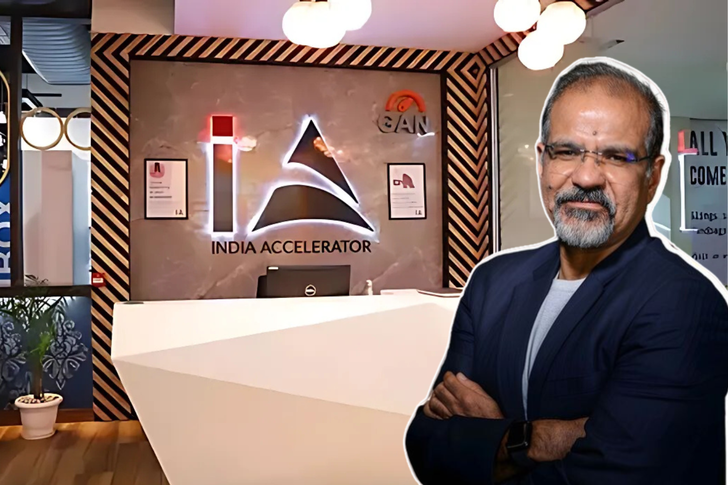 The image appears to showcase the India Accelerator office reception area, featuring its illuminated logo on the wall, and includes a prominent figure in the foreground, likely associated with the organization.
