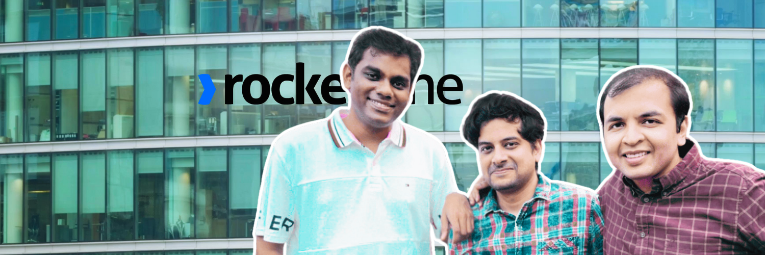 The image is a promotional banner featuring the three founders of Rocketlane, depicted in front of a modern office building. They are smiling and standing close together, suggesting a strong team dynamic. The company's logo, "Rocketlane," is prominently displayed in the upper right corner of the image, set against the building's glass façade.
