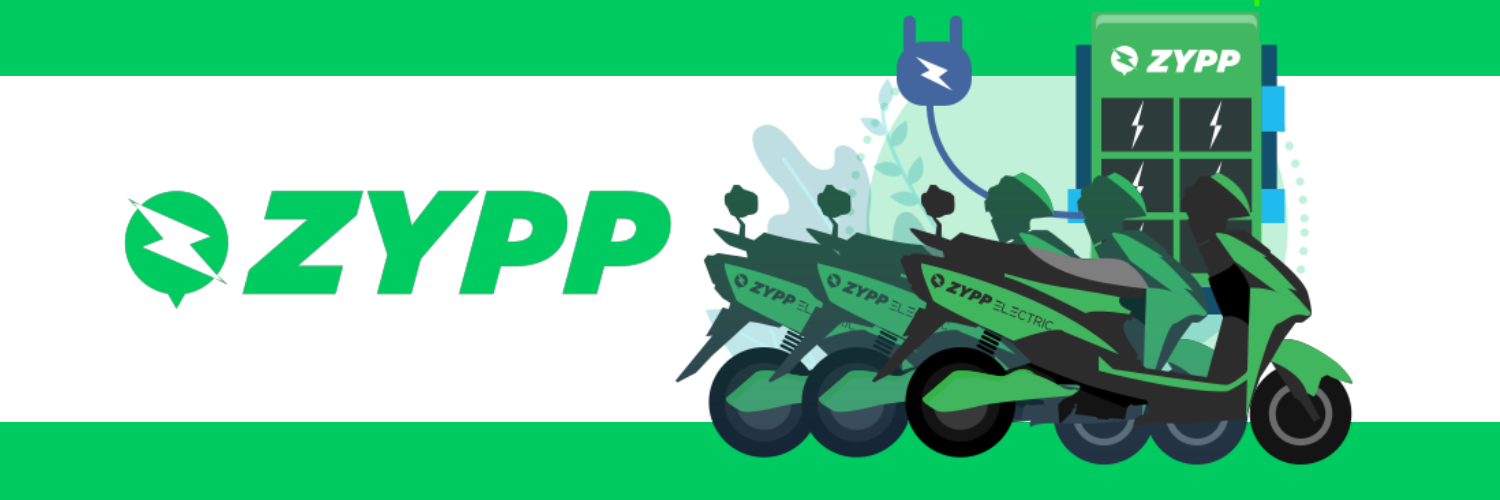 A banner featuring the logo and branding of Zypp, an electric scooter service. The left side displays the Zypp logo in large white letters on a green background. On the right, a stylized illustration shows a lineup of electric scooters in green and black, docked at a charging station adorned with the Zypp logo and lightning bolt symbols, set against a background of abstract green shapes and leaves, indicating an eco-friendly service.