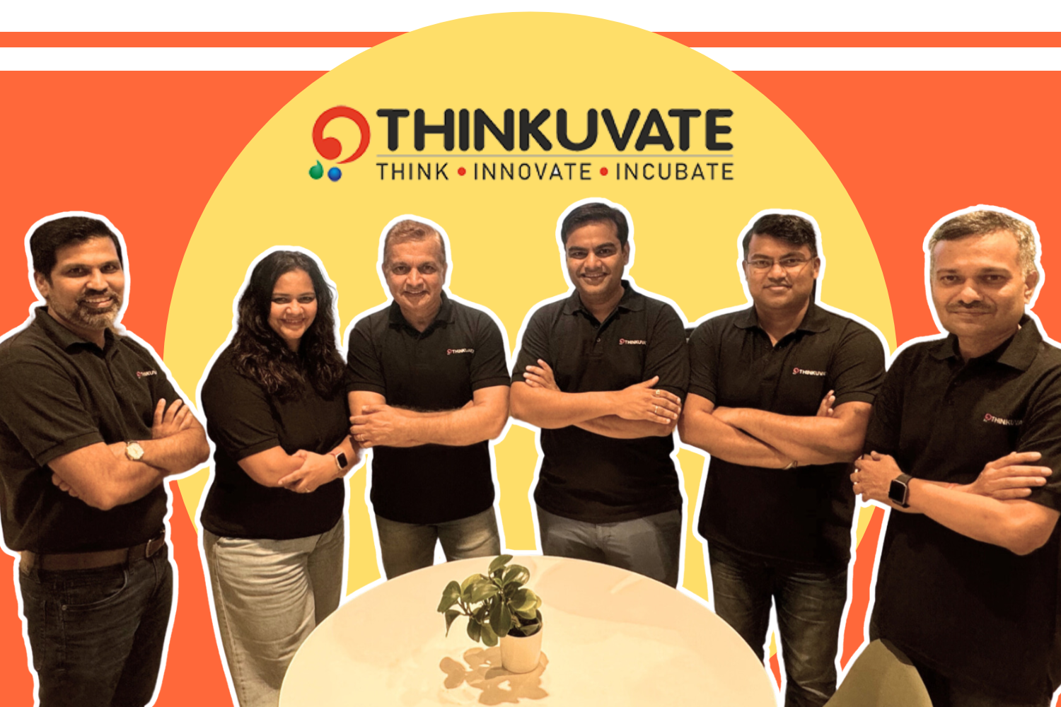 This image features the founders of Thinkuvate, with six individuals standing confidently, all wearing matching black polo shirts displaying the Thinkuvate logo. The group consists of three men on each side and a woman in the middle. They pose with crossed arms, exuding a sense of unity and professionalism. The backdrop includes vibrant tones of orange, red, and yellow, with the Thinkuvate logo above them, along with the tagline "THINK · INNOVATE · INCUBATE." A small plant on a round table is in the foreground, symbolizing growth and creativity.
