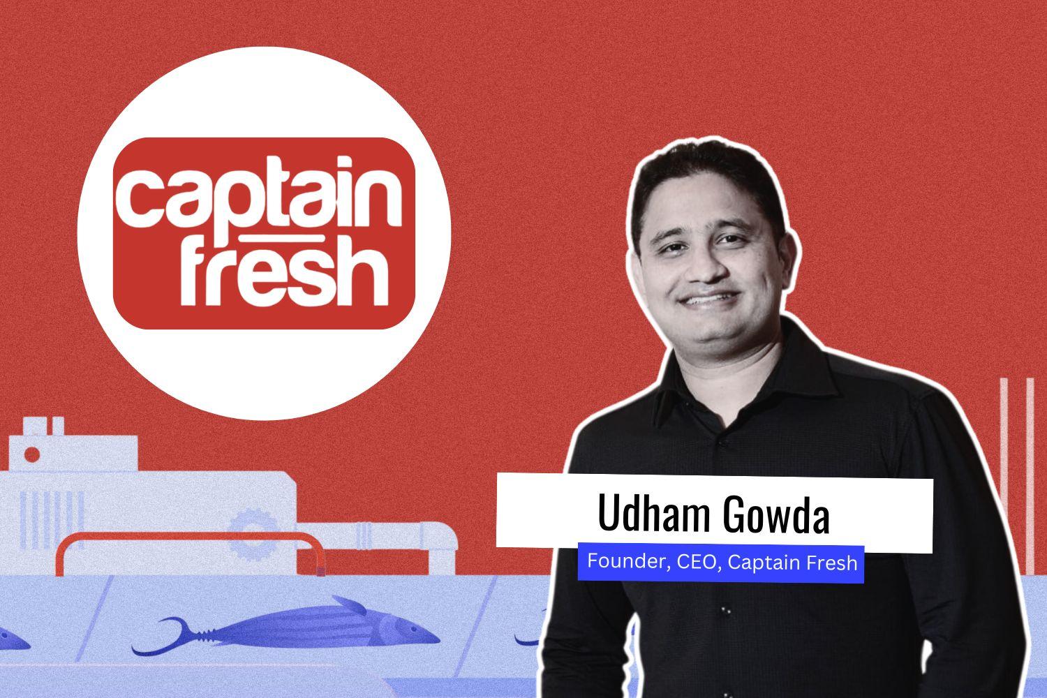 A digital graphic featuring Udham Gowda, the Founder and CEO of Captain Fresh. He is wearing a black shirt and is smiling. The background has a red theme with an illustration of fish and processing equipment. The "Captain Fresh" logo is prominently displayed in a white circle. His name and title are written on a white and blue text banner.