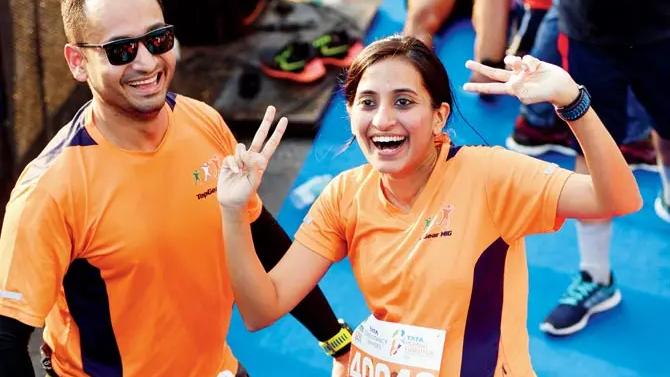 Vineeta Singh, visibly six months pregnant, is participating in the Tata Mumbai Marathon, enthusiastically running the 21km race alongside her husband, Kaushik Mukherjee. Both are in high spirits, captured here sharing a joyful moment in matching orange tops. Singh's bib number "40040" is clearly visible. This photo not only showcases their athletic spirit but also Singh's remarkable determination and vitality during her pregnancy.