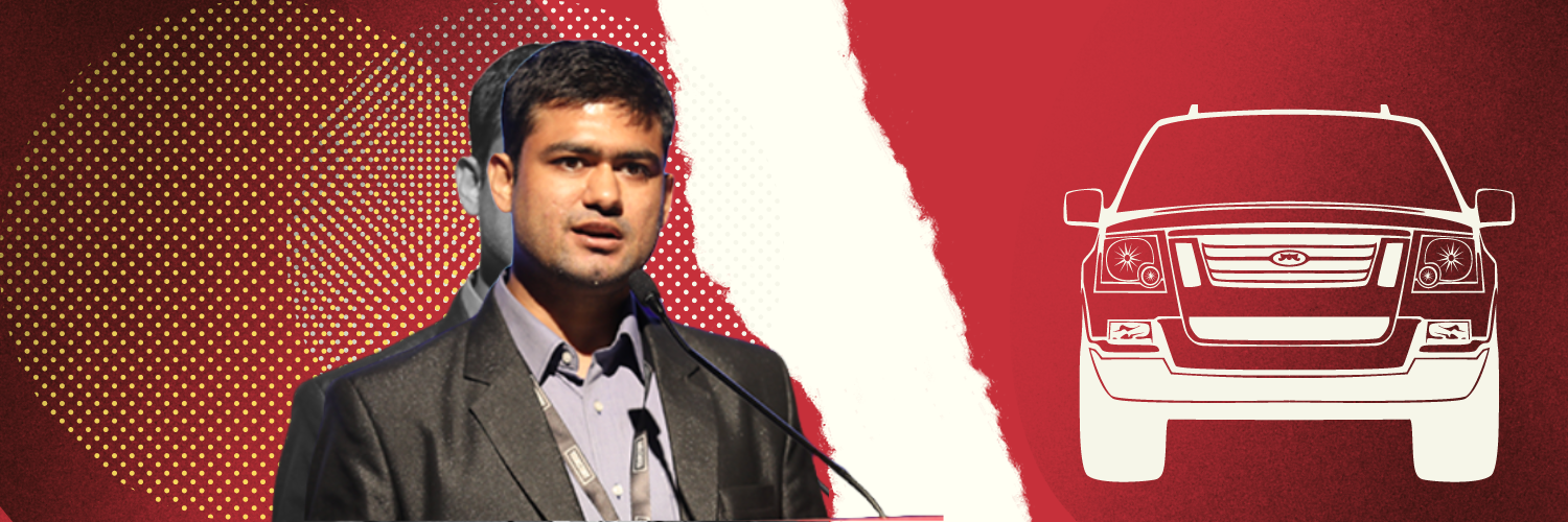 The image features a graphic design with a red and white theme, incorporating a half-body portrait of Sanjeev Sharma, the founder of Swaayatt Robots, speaking at a podium. To his left, there's a large, circular, dotted pattern on a red background. On the right side of the image, against a white background, is a stylized red illustration of an autonomous vehicle. This design effectively conveys the theme of innovation and technology in the context of autonomous driving.