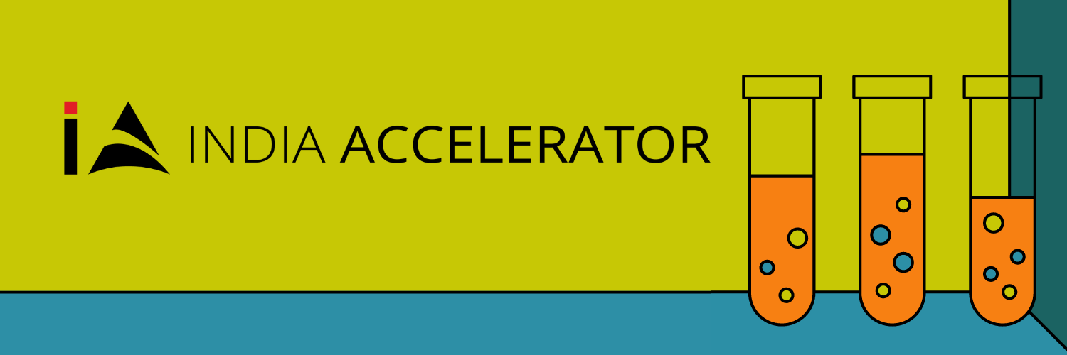 Banner image for India Accelerator featuring their logo and three laboratory test tubes with various levels of orange and blue liquid, symbolizing innovation and experimentation in startups.