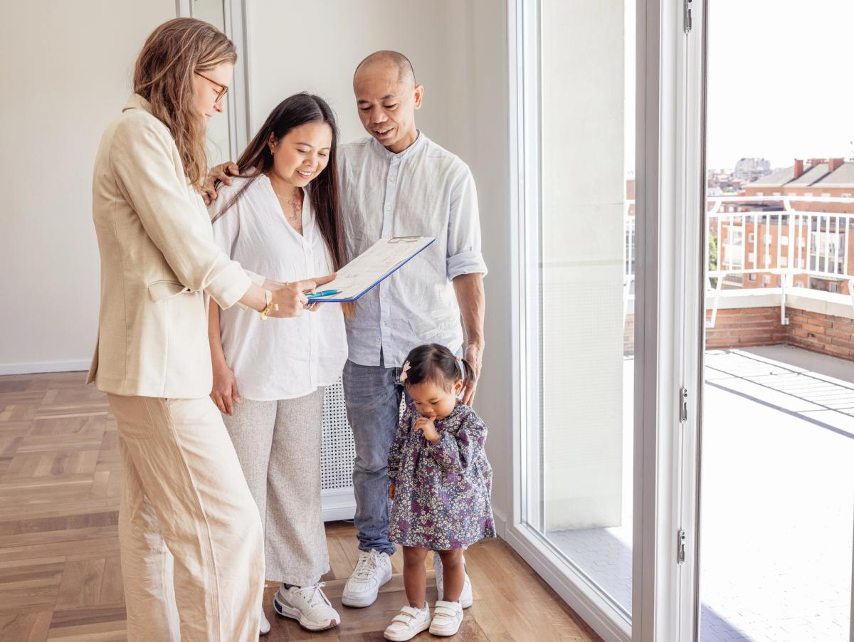Real estate agent showing floor plans to a family with child