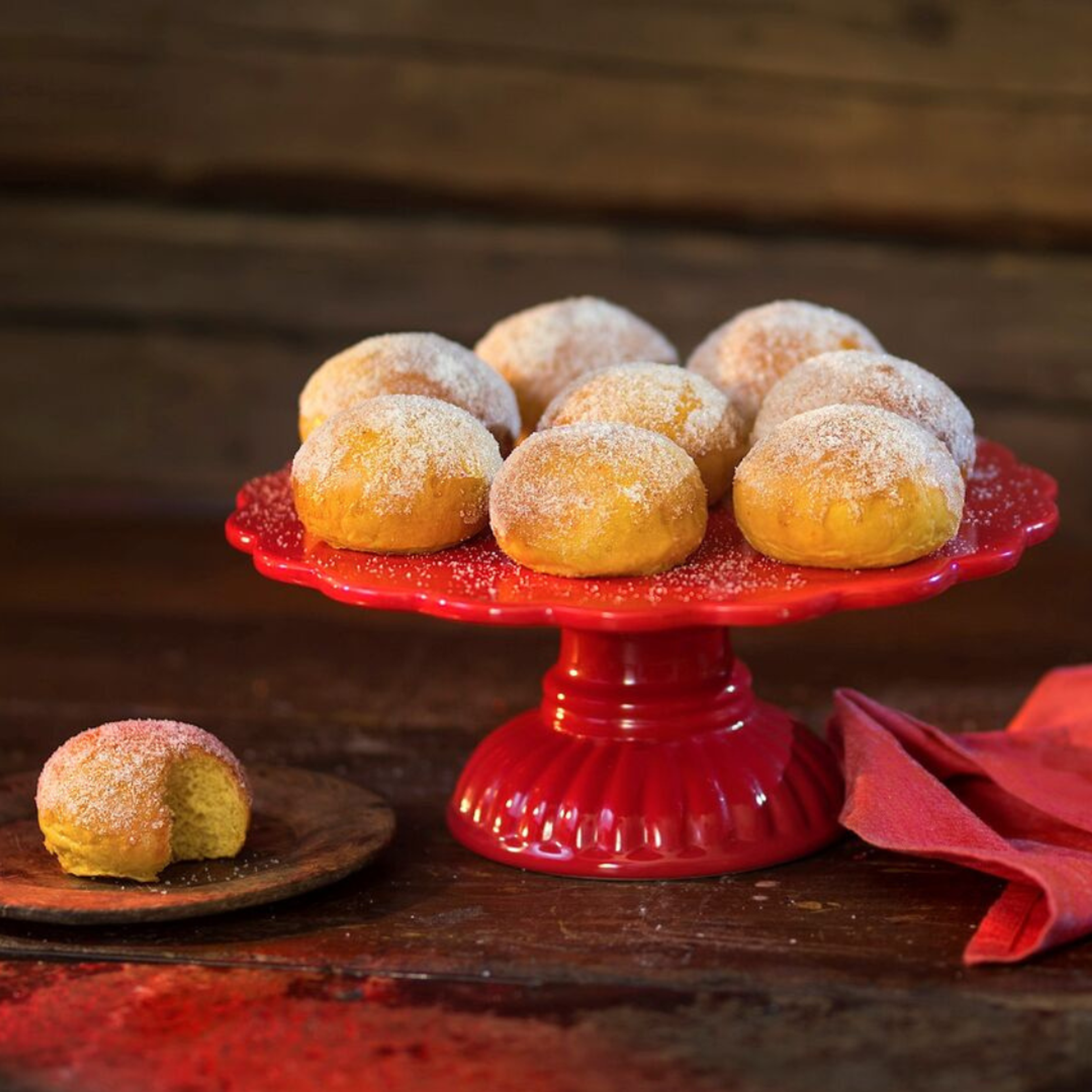 Släta lussebullar toppade med socker ovanpå ett rött tårtfat